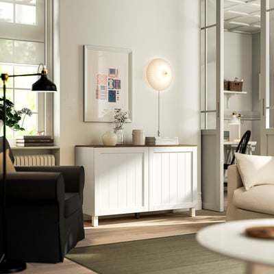 Modern living room with white BESTÅ sideboard, black sofa, green rug, and art.