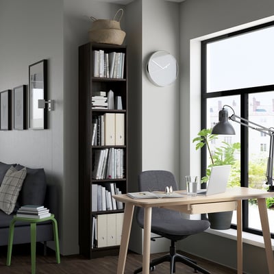 Modern home office with BILLY bookcase, grey chair, desk with laptop, and cosy armchair.