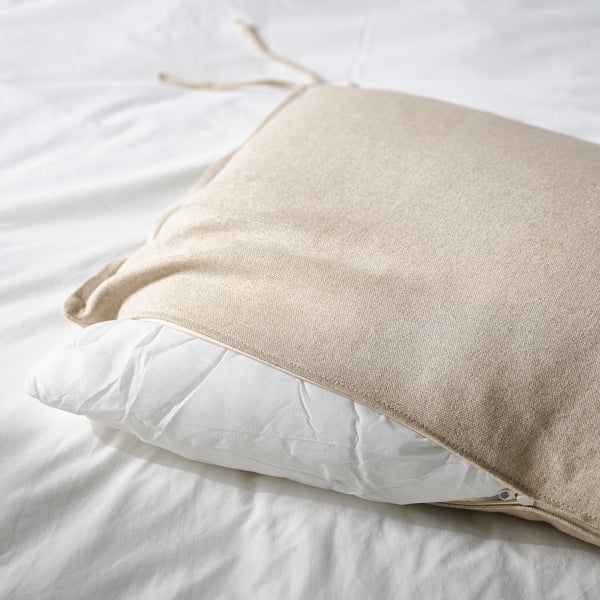 Pillows on bed: one with zip, both on white sheets.