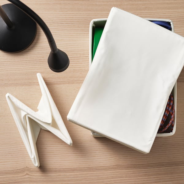 Wooden desk with white storage box, lamp, and clips.
