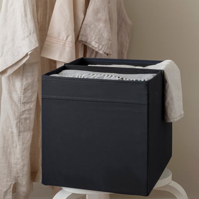 Black storage box with divider on white stand, organising towels.