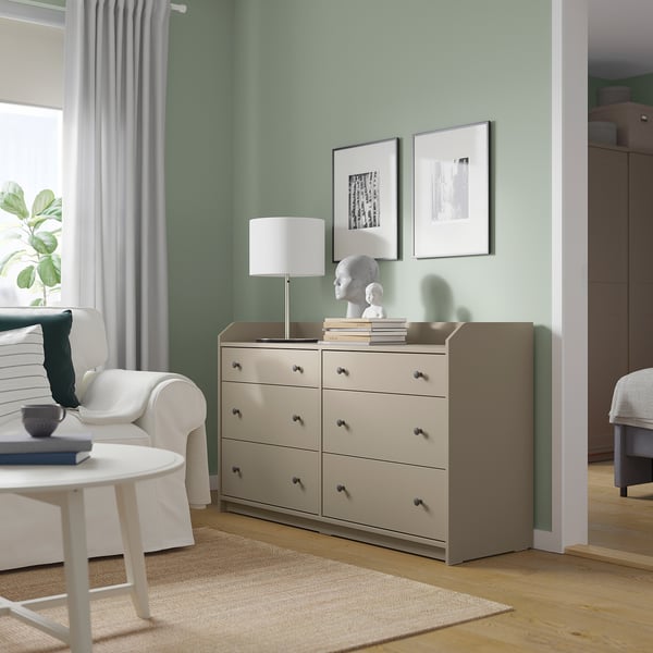 Minimalist living room with a beige HAUGA chest of 6 drawers, lamp, plant, and art.