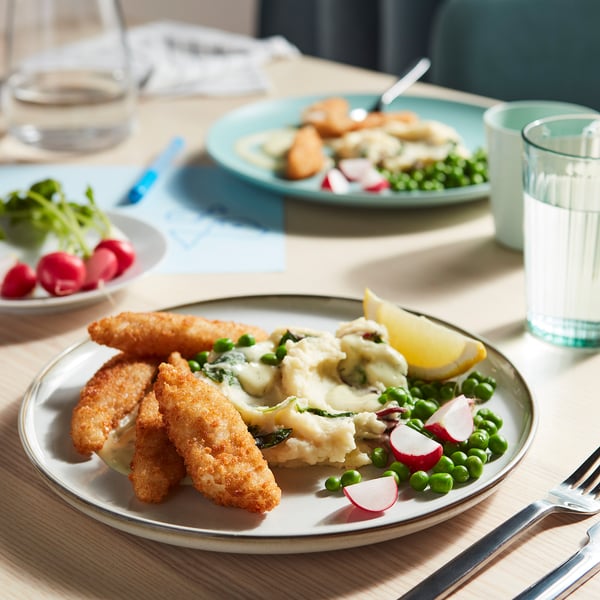 Plate with golden fish bites, peas, radishes, lemon, creamy mash.