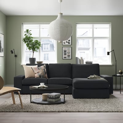 Grey KIVIK sectional sofa in green room with large windows.