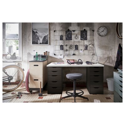 Home office setup featuring LAGKAPTEN desk with two dark brown drawers and white top. Accessorised with stool, lamp, and wall decor.