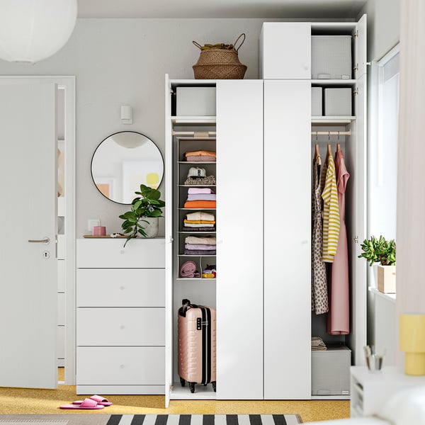 Organised closet with shelves, hanging clothes, and pink suitcase.