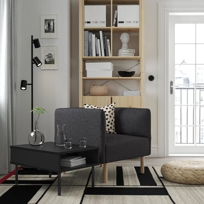 Modern grey sofa in stylish room. Bookshelf, window, side table, polka dot cushion, clean minimalist ambiance.