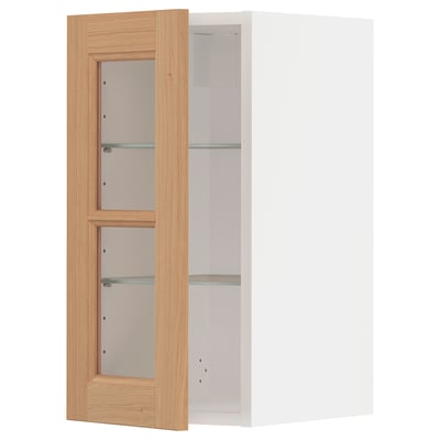 A METOD kitchen cabinet with oak doors and glass shelves. Its a wall-mounted unit with a natural wood look, perfect for a warm and inviting kitchen.