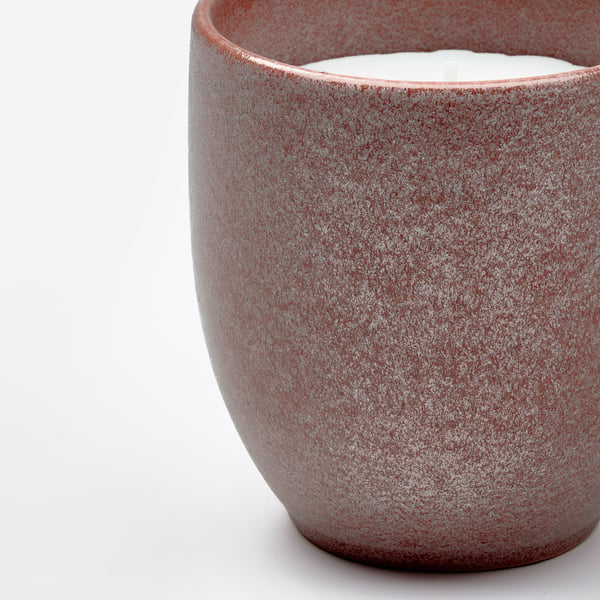 A rustic stoneware candle with a speckled glaze and a visible white wick. It emits a warm, inviting atmosphere, perfect for home decor.