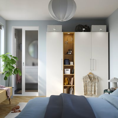 Bedroom with PAX wardrobe, mirror, plant, blue bed. Or bedroom featuring PAX wardrobe, mirror, plant, blue bed.