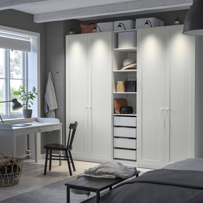 A white PAX wardrobe with drawers and shelves, tall and well-lit.