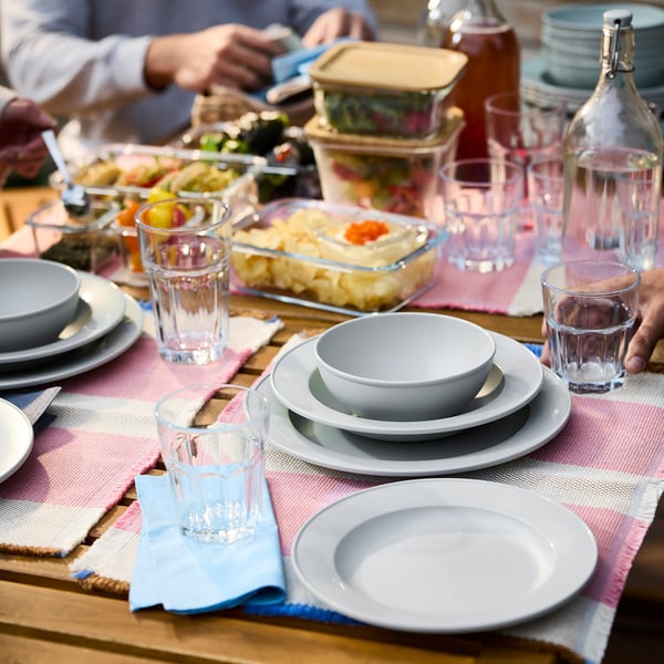 Dinner table set with SIMKRABBA plates, glasses, food, and cutlery.