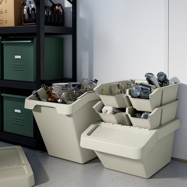 In there are stacked white SORTERA storage bins with compartments, holding various small items, placed near a shelving unit.