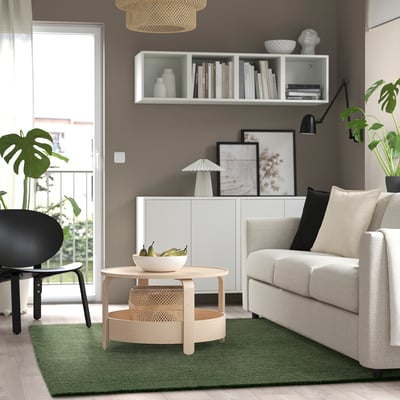 Modern living room with STOENSE green rug, white sofa, wooden coffee table, and wall decorations.