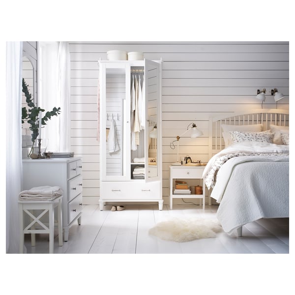 Bright white minimalist bedroom with TYSSEDAL cabinet, wooden walls, bed, pillows, and rug. Cosy, clean look.
