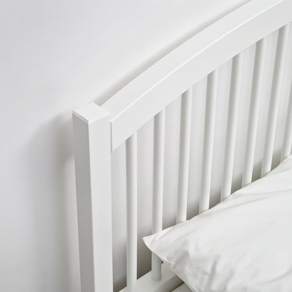 Crisp white bed frame with sleek, sturdy design; elegant spindles and headboard, inviting cleanliness and comfort.