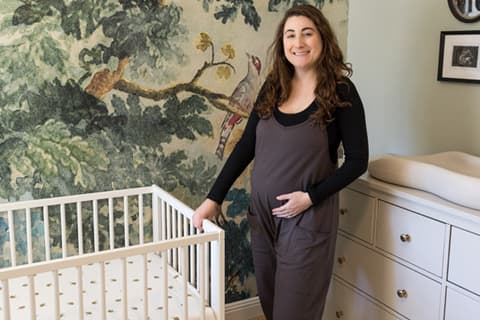 woman standing in baby nursery next to crib and changing table