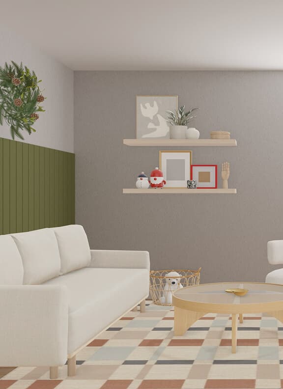 A virtual holiday living room in IKEA Kreativ featuring a white sofa, lounge chair, and round wooden coffee table on a patterned rug with green wainscoting, wreath, and festive décor.