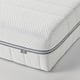 IKEA mattress corner detail. Close-up of firm, white mattress with blue trim and IKEA tag, showing quality texture and layers.