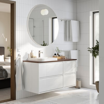 Modern white bathroom setup. ÄNGSJÖN vanity with 4 drawers, marble sink, round mirror, and hanging towels.