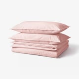 Stack of 4 pink cotton pillowcases, soft and square-shaped.