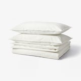 A stack of three white soft cotton duvet covers with concealed press studs and envelope closure pillowcases.