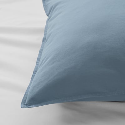 A close-up of a soft, blue pillowcase, showcasing its smooth, pre-washed cotton texture and edge detail.
