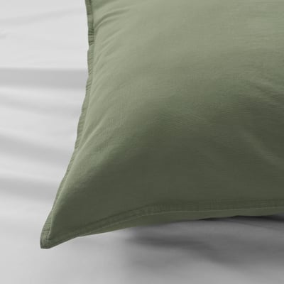 Close-up of a soft, green pillowcase on a bed.