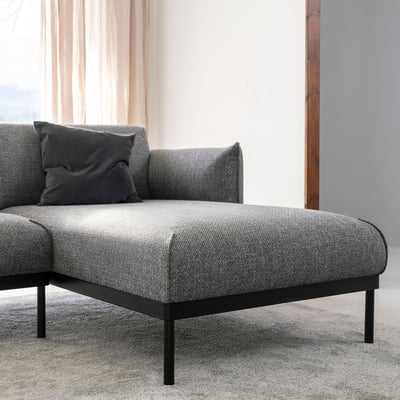 Modern grey sectional sofa with black legs, minimalist design.