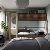 Modern bedroom with AULI sliding wardrobe. Minimalist, grey, and plant near entrance.