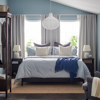 Bedroom with blue-striped BERGPALM comforter, lamps, and curtains.