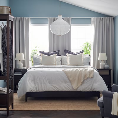 Bedroom with white BERGPALM comforter, striped curtains, and bedside table lamps.