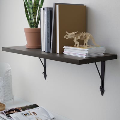 Black wall shelf holds books, plant, and decor.