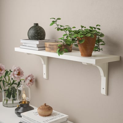 White wall shelf displays books, plants, and decor. Holds up to 10 kg evenly distributed.