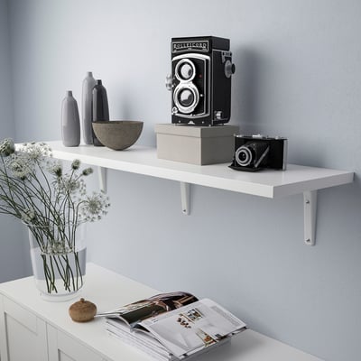 White wall shelf displaying an old camera and vases.