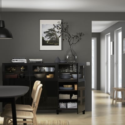 Modern sideboard with adjustable shelves, displaying plates and bowls, topped with a vase and decorative branches.