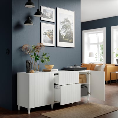 Modern living room with BESTÅ sideboard, record player, dark blue walls, photos, and black pendant lights.