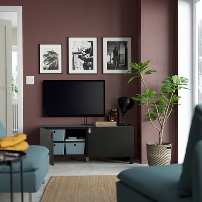 Modern living room with maroon wall, black BESTÅ tv bench, flat screen tv, and adjustable shelves.