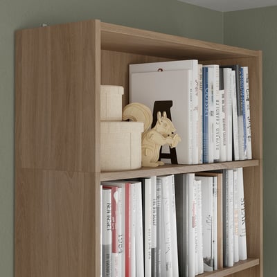 Wooden bookshelf with multiple shelves holding books and decorative items, extending vertically for extra storage.