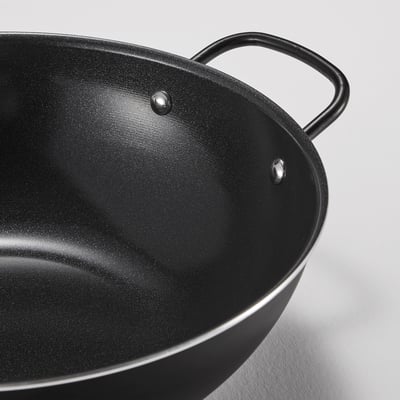Black wok with two sturdy handles and non-stick coating on white surface.