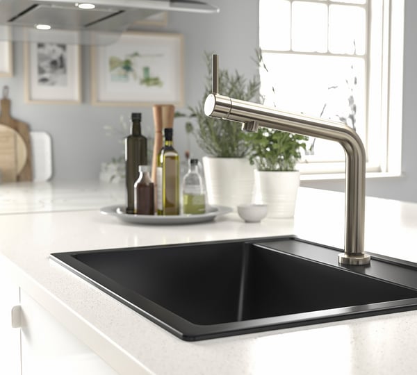 Stainless steel BOSJÖN kitchen tap on white counter with black sink; modern, eco-friendly design.