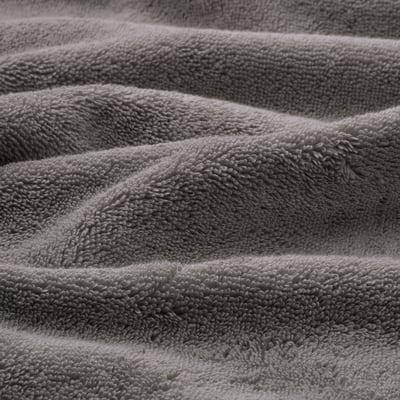 Close-up view of thick, soft, grey towels with textured weave and decorative border, showcasing high-quality craftsmanship.