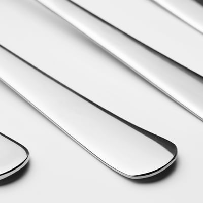 Multiple polished stainless steel spoons neatly arranged, showcasing sleek, reflective surfaces and durable quality.