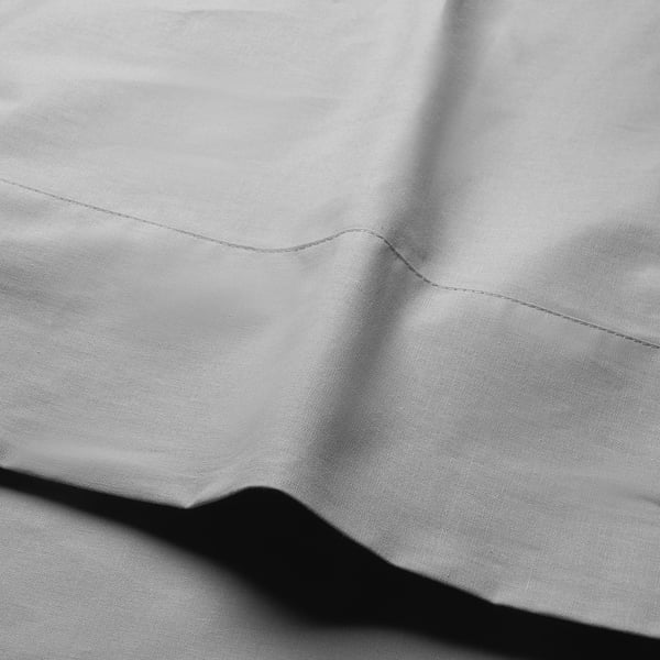 Black and white close-up of smooth, wrinkled cotton fabric, showcasing even stitching and luxurious texture.