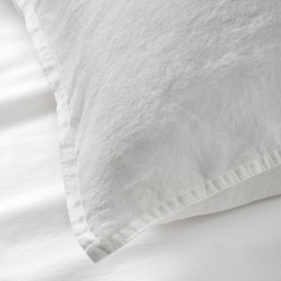 A close-up of a white linen pillowcase showcasing its soft, slightly textured fabric and clean, precise stitching.