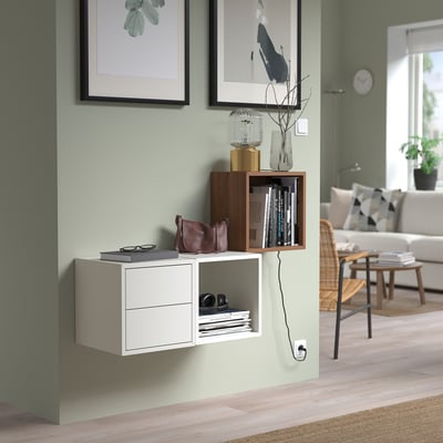 Modern EKET storage units with shelves, books, and decor against a sage green wall.