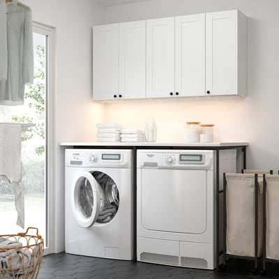 Modern laundry room with ENHET white units, washing & drying machines, countertop, and storage. Clean & bright design.