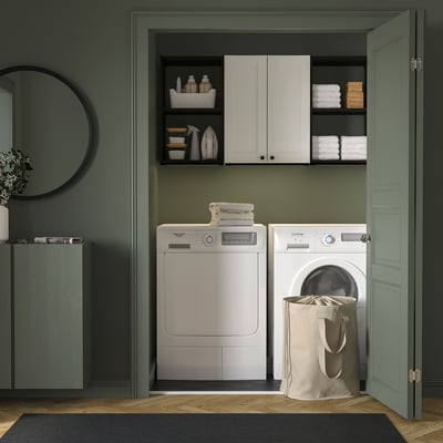 Modern laundry closet, green walls, white ENHET storage with washer, dryer, towels, and basket.
