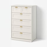 Depicts a white FÅGELFJÄLLET chest of drawers with six drawers, featuring brass-effect handles and a crafted design.