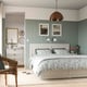 Neat bedroom with FÅGELFJÄLLET off-white bed, matching dresser, and hanging light. Bed has a patterned duvet and pillow, flanked by wall lamps.